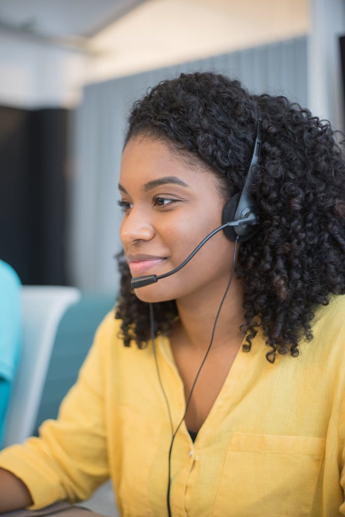Services Focused call center agent with curly hair in a yellow blouse providing customer support.